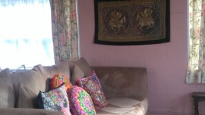 A living room with a beige sofa, colorful pillows, a framed artwork on the wall, and a striped rug. - Pear Tree Farm (Glastonbury)