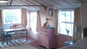 A room with a bed, a dresser, a table with chairs, and a window with curtains. - Pear Tree Farm (Glastonbury)
