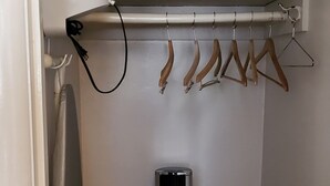 A small closet with a hanging rack, an iron, and a radiator. - Townhouse Motel (San Francisco)