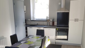 Een functionele keuken met een eethoek, met een inbouwoven, een spoelbak en een raam voor natuurlijk licht.