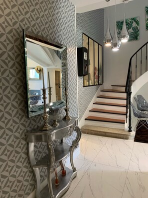 Una escalera de diseño moderno, una consola con objetos decorativos y un revestimiento de pared con estampado.