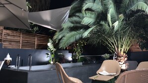 Ein Außenbereich mit Korbmöbeln, einer Bar und einer großen Palme.