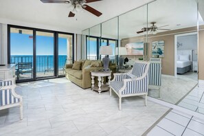 Un vaste espace de vie avec un balcon donnant sur la mer, aménagé avec un canapé, des fauteuils et une table basse.