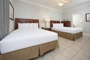 A hotel room with two beds, a ceiling fan, a nightstand, a lamp, and a framed picture on the wall. - Condo 71215 at Phoenix 7 **See why our guests come back!** (Orange Beach)