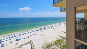 A beach with numerous umbrellas and sun loungers, a clear blue sky, and the ocean.