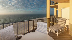 Ein Balkon mit Blick auf den Ozean, ein Stuhl und ein Tisch.