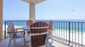 A balcony with a view of the beach, featuring a table and four Adirondack chairs. - Two Bedroom Phoenix 5 Condo 1215 (Orange Beach)