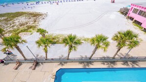 Zona de piscina con sillas de descanso, una piscina y una playa al fondo.