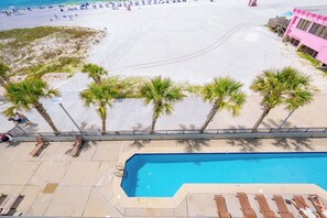 Un espace piscine avec des chaises longues, une piscine et une plage en arrière-plan.