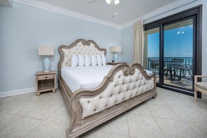 A bedroom with a large bed, two bedside tables, a chair, and a balcony with a view. - Three Bedroom ~ Phoenix VII ~ Comes with Parking! (Orange Beach)