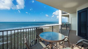 A balcony with a glass table and chairs, overlooking a beach and ocean. - Three Bedroom ~ Phoenix VII ~ Comes with Parking! (Orange Beach)
