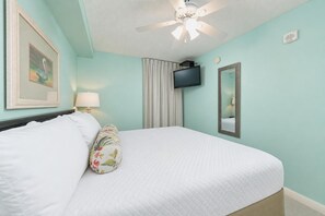 A hotel room with a bed, a ceiling fan, a flat-screen TV, a mirror, and a painting on the wall. - It is just like a CONDO…it's the Phoenix Hotels! FREE Wifi - Full Kitchen (Gulf Shores)