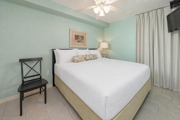A hotel room with a bed, a chair, a ceiling fan, a TV, and a painting on the wall. - It is just like a CONDO…it's the Phoenix Hotels! FREE Wifi - Full Kitchen (Gulf Shores)