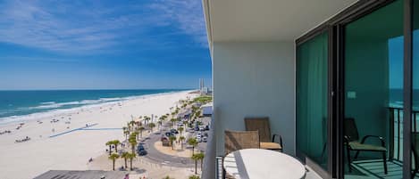 Een balkon met uitzicht op een strand, een tafel en stoelen.