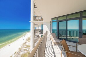 A balcony with a view of the beach and ocean.