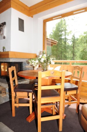 A wooden dining table with chairs, a vase with flowers, and a fireplace. - Superb duplex in luxury apartment at foot of slopes (Val-D'isère)