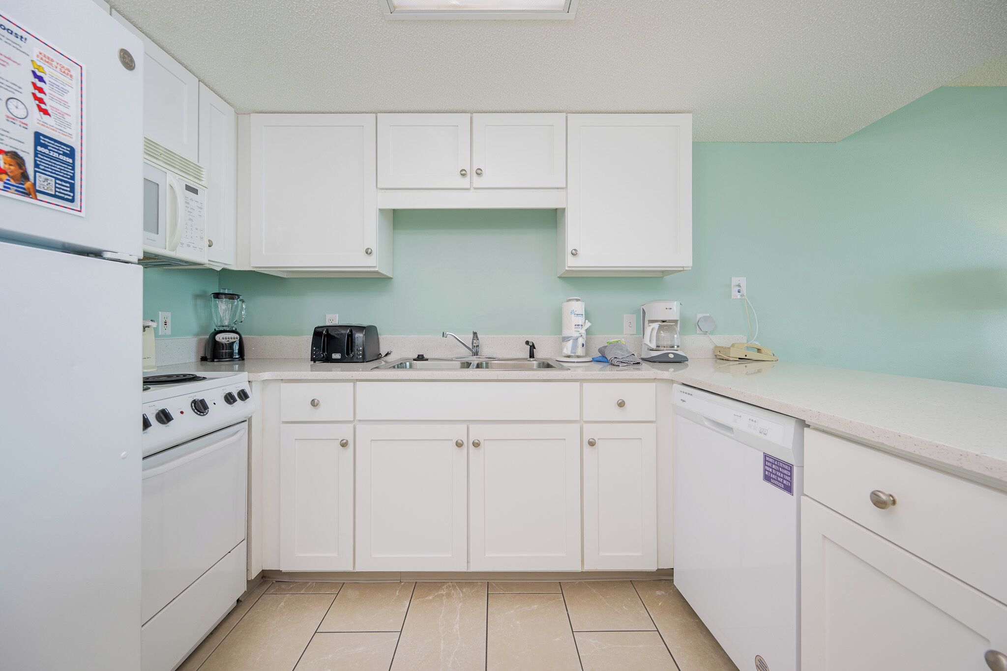 A kitchen with white cabinets, a stove, a microwave, and a sink.