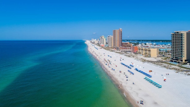 Eine Küstenstadt mit breitem Strand, hohen Hotels und klarem, blauem Wasser.