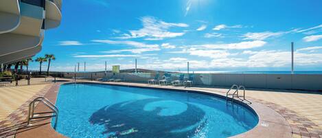 A swimming pool with a clear blue sky and a sun in the background.