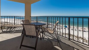 Un balcon avec une table et des chaises donnant sur une plage.