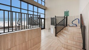 Un escalier offrant une vue sur la plage, un panneau indiquant les règles d’utilisation du jacuzzi et un tuyau bleu sur la droite.