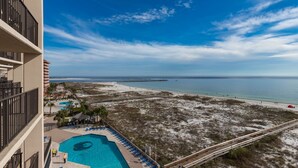 A hotel with a pool, beach view, and a boardwalk.