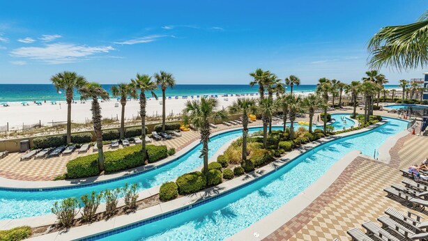 Ein Resort mit Poolbereich, Palmen und Strand.