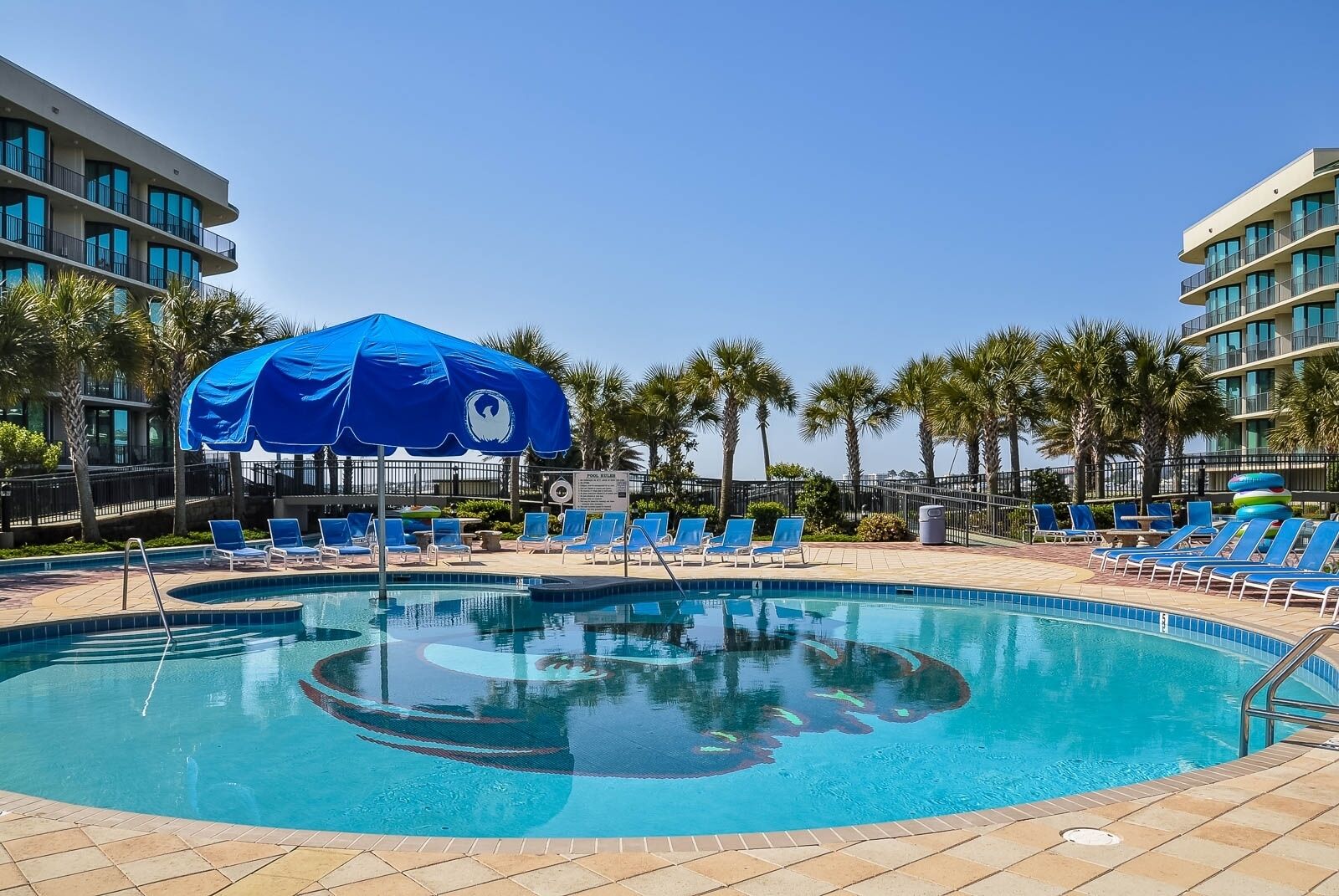 Una piscina con lettini blu e un ombrellone blu.
