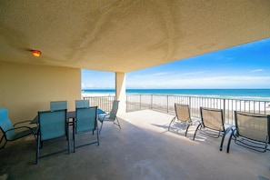 A covered outdoor area with chairs and tables, overlooking a beach and ocean. - PREMIUM 2 Bedroom @ P5 ~ Great Rates (Orange Beach)