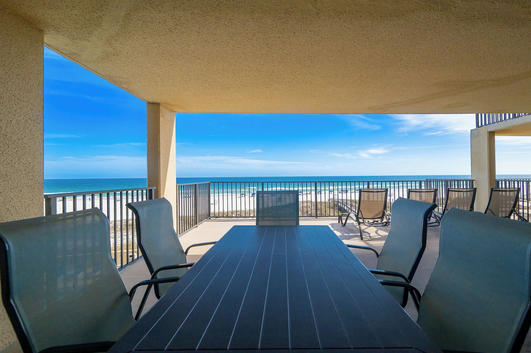 Ein Balkon mit Tisch und Stühlen mit Blick auf Strand und Meer.