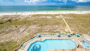 A beach resort with a swimming pool, beach chairs, umbrellas, and a clear view of the ocean. - Phoenix VII Two Bedroom Condo ~ GULF FRONT (Orange Beach)