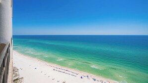 Blick auf einen Strand mit klarem, blauem Wasser und sandigem Ufer.