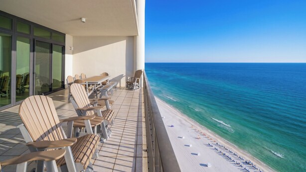 Ein Balkon mit Stühlen und Tischen mit Blick auf einen Strand.