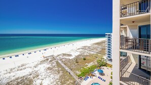 A beach view from a hotel balcony with a pool and lounge chairs. - Splash Pad and New Amenities! Phoenix East 2BR 2BA (Orange Beach)