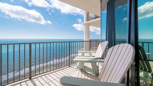 A balcony with a view of the ocean, two white chairs, and a glass door. - The Oasis at Orange Beach, formerly known as Phoenix West II, Unit 2204 (Orange Beach)