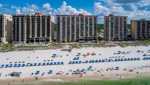 A beachfront hotel with multiple high-rise buildings, a sandy beach, and numerous umbrellas. - SAVE MORE! ~ 2 Bedroom ~ Phoenix III (Orange Beach)