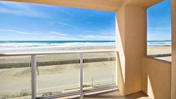 A balcony with a view of the beach and ocean.