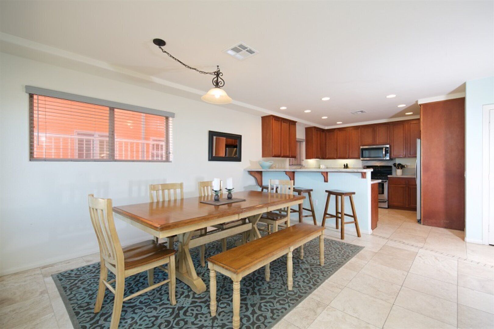 A modern kitchen with wooden cabinets, a central island, and a dining area with a wooden table and chairs.
