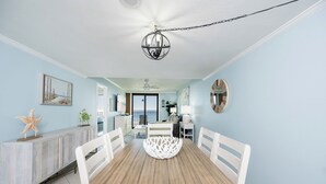 A dining area with a wooden table and white chairs, a decorative bowl in the center, and a ceiling fan. - 2 Bedroom BEACH FRONT! Phoenix I (Orange Beach)