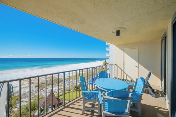 A balcony with a view of the beach and ocean.