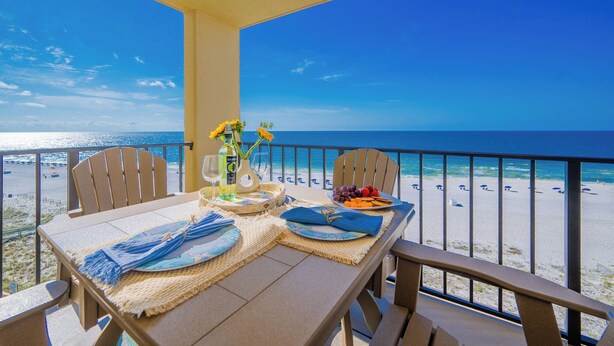 A balcony with a table set for two, overlooking a beach with a clear view of the ocean. - 2 Bedroom @ Phoenix 3! (Orange Beach)