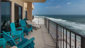 A balcony with turquoise chairs, a concrete floor, and a view of the ocean and beach. - PENTHOUSE CONDO!!!! 3 Bedroom - BEACH FRONT (Orange Beach)