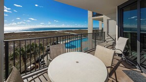 Un balcón con piscina, sillas y vista a la playa y al océano.
