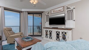 A living room with a leather chair, a wooden coffee table, a TV, and a 'Welcome' sign.