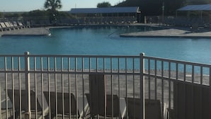 Una piscina con varias pistas, rodeada de sillas de descanso y una zona cubierta.