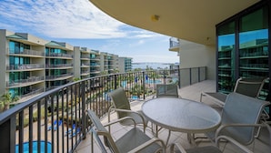 A balcony with a view of a swimming pool and adjacent buildings. - Tranquil 3BR at Phoenix on the Bay Unit 1415 (Orange Beach)