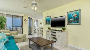 Salón con sofá, mesa de centro, televisor y muebles de almacenaje. Tiene un balcón con vistas.