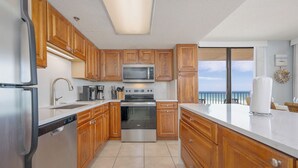 Une cuisine moderne avec des meubles en bois, des appareils électroménagers en acier inoxydable et une vue sur l’océan.