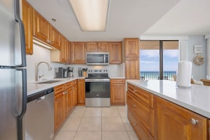 A modern kitchen with wooden cabinets, stainless steel appliances, and a view of the ocean. - Three Bedroom on the 4th Floor…Comes with Reserved Parking (Orange Beach)