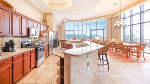A spacious kitchen with granite countertops, wooden cabinets, and a large island. - The Oasis at Orange Beach, formerly known as Phoenix West II, Unit 201 (Orange Beach)
